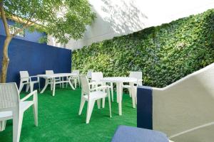a room with white tables and chairs and a green wall at Patio79 Aveiro in Aveiro
