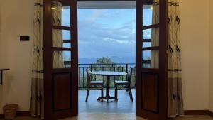 a door open to a balcony with a table and chair at Green Mount View Cottage in Ella