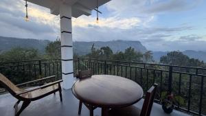 a table and chairs on a balcony with a view at Green Mount View Cottage in Ella