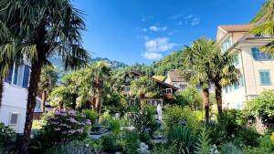 a garden in front of a house with palm trees at Bio Bed & Breakfast Froschkönig in Gersau