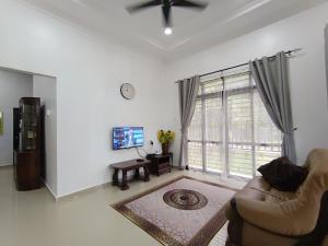 a living room with a couch and a large window at NikNa Homestay Batu Rakit - WIFI Netflix in Kampong Ru Tujoh