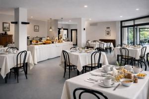 a dining room with white tables and chairs at Hotel Granducato in Montepulciano