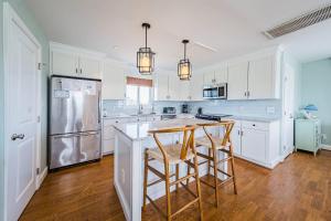 a kitchen with white cabinets and a island with bar stools at Arcadia - Duck, Caffey's Inlet, Ocean Views, 50 Yards to Beach, Pool, Pets OK, Cul-de-sac Location in Duck