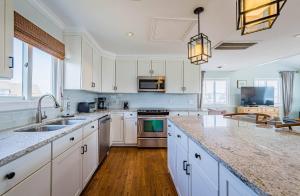 a kitchen with white cabinets and marble counter tops at Arcadia - Duck, Caffey's Inlet, Ocean Views, 50 Yards to Beach, Pool, Pets OK, Cul-de-sac Location in Duck