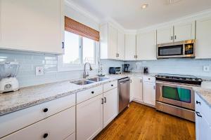 a large kitchen with white cabinets and a sink at Arcadia - Duck, Caffey's Inlet, Ocean Views, 50 Yards to Beach, Pool, Pets OK, Cul-de-sac Location in Duck +43 photos