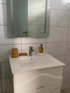 a bathroom with a white sink and a mirror at Heshima's Apartment for Business in Macouria