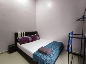a small bedroom with a bed with purple pillows at NikNa Homestay Batu Rakit - WIFI Netflix in Kampong Ru Tujoh