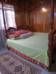 a wooden bed with pillows on it in a room at Antique Villa in Gampola