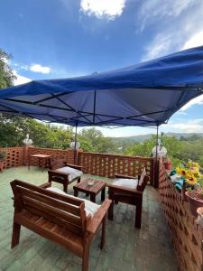 a patio with benches and a blue umbrella at Refugio Blue Hill in Villa Cerro Azul