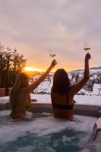 two women sitting in a hot tub with glasses of wine at The Pines Bucegi Lodge in Bran