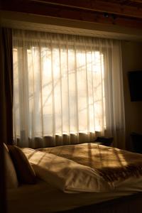 a bed in front of a window with a curtain at The Pines Bucegi Lodge in Bran