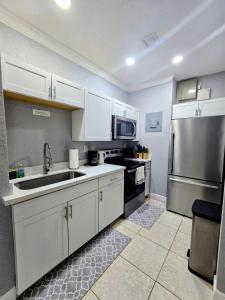 a kitchen with white cabinets and a stainless steel refrigerator at Cozy Green Apartment in Homestead