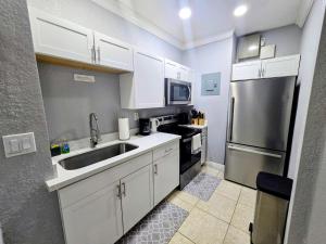 a kitchen with white cabinets and a stainless steel refrigerator at Cozy Green Apartment in Homestead +10 photos