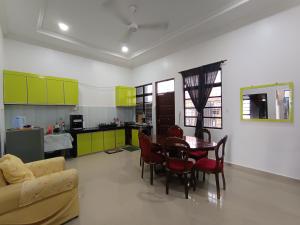 a living room with a table and chairs and a kitchen at NikNa Homestay Batu Rakit - WIFI Netflix in Kampong Ru Tujoh