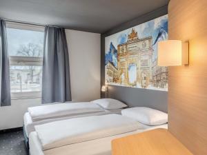 two beds in a room with a painting on the wall at B&B HOTEL München-Schwabing in Munich