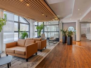 an office lobby with couches and tables and windows at B&B HOTEL München-Schwabing in Munich +19 photos