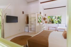 a white bedroom with a bed and a tv at Beco das Flores in Mata de Sao Joao