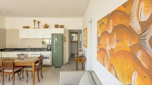a kitchen and dining room with a large painting on the wall at Apartamento do Paulão in Ubatuba