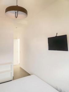 a bedroom with a bed and a tv on the wall at Apartamento do Paulão in Ubatuba
