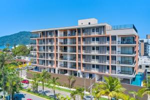 an apartment building with palm trees and a street at Apartamento do Paulão in Ubatuba