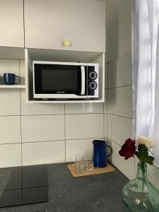 a microwave on a wall with a vase of flowers at Heshima's Apartment for Business in Macouria +15 photos