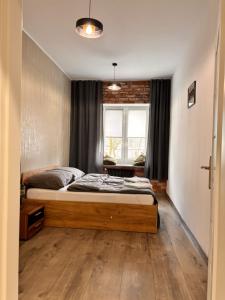 a bedroom with a bed and a large window at Apart Brzeg in Brzeg