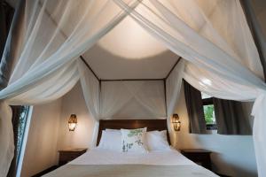 a bedroom with a canopy bed with white curtains at AZORAI - Hotel Boutique in Santa Cruz Cabrália +34 photos
