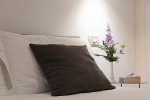 a pillow on a bed with a vase with a plant at Residence Victoria in Trieste