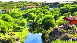 un río en un parque con un puente y árboles en Los Ancares Resort en Mina Clavero