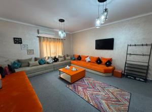 a living room with orange couches and a flat screen tv at Chateau Nougat, Marrakech in Marrakesh