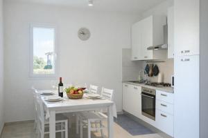 a white kitchen with a white table and chairs at Residenza Sa Olia in Budoni +13 photos