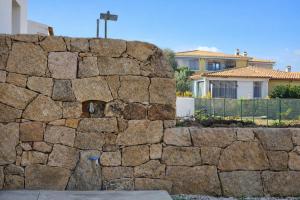 a stone wall with a house in the background at Residenza Sa Olia in Budoni