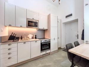 a kitchen with white cabinets and a table with chairs at Frida Loft in Pécs