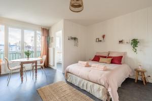a bedroom with a large bed with a table and a window at La Cabane Parking privatif et Balcon in La Riche