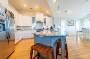 a kitchen with white cabinets and a island with a counter top at Sea Fever - Duck, Saltaire, 130 Yds to Beach, Ocean View, Pool, Hot Tub, Tiki Bar, Flex Stays in Duck