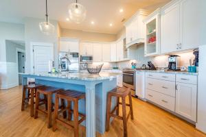 a kitchen with white cabinets and a blue island with stools at Sea Fever - Duck, Saltaire, 130 Yds to Beach, Ocean View, Pool, Hot Tub, Tiki Bar, Flex Stays in Duck