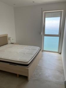 a bedroom with a bed and a large window at Ocean View Beach Apartment in Shëngjin