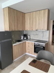 a kitchen with wooden cabinets and a black refrigerator at Ocean View Beach Apartment in Shëngjin