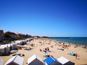 a crowd of people on a beach with umbrellas at La Douce Escale studio in Courseulles-sur-Mer