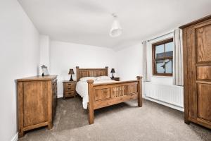 a bedroom with a bed and wooden furniture and a window at Cappaghmore by Escape Ordinary in Portstewart