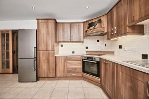 a kitchen with wooden cabinets and a stainless steel refrigerator at Cappaghmore by Escape Ordinary in Portstewart