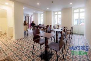 a restaurant with tables and chairs and people sitting at tables at Hostel Casa São Pedro in Angra do Heroísmo