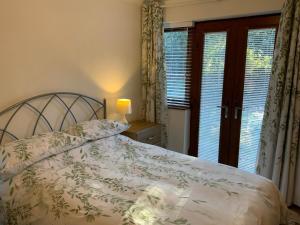 a bedroom with a bed and two windows with curtains at Daisy Cottage in Polegate +25 photos