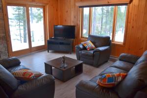 a living room with couches and a flat screen tv at Les Chalets du Lac Serein (Milot) in Saint Ludger de Milot
