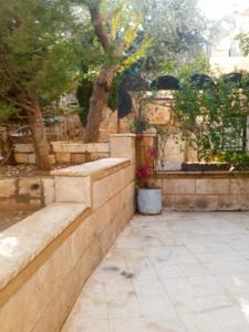 a stone retaining wall with trees and flowers in a garden at Flowers in Jerash
