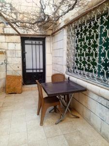 a table and chairs in a patio with a window at Flowers in Jerash