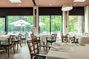 a restaurant with white tables and chairs and windows at Hôtel-Musée Premières Nations in Wendake