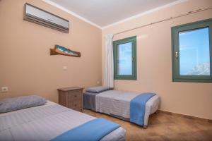 two beds in a room with two windows at Sky & Sea View Retreat in Telendos