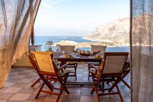 a table and chairs on a balcony with a view of the ocean at Sky & Sea View Retreat in Telendos
