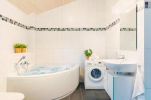a bathroom with a tub and a sink and a washing machine at Haus Stressfrei - Nordhorn in Nordhorn